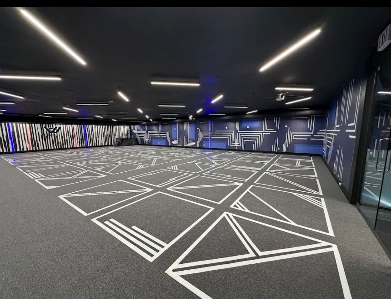 The Another World free-roam arena with geometric floor tape and W-logo back wall